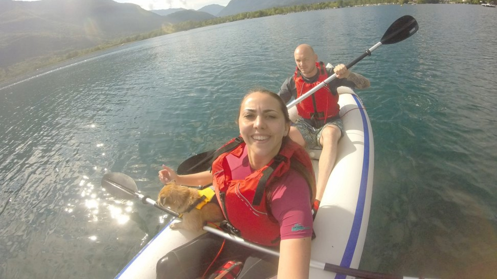 Rachel on a kayak with a dog and a man with hill in background