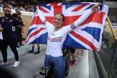 Neah Evans stands with Great Britain flag after winning points race at Track World Championships 2022