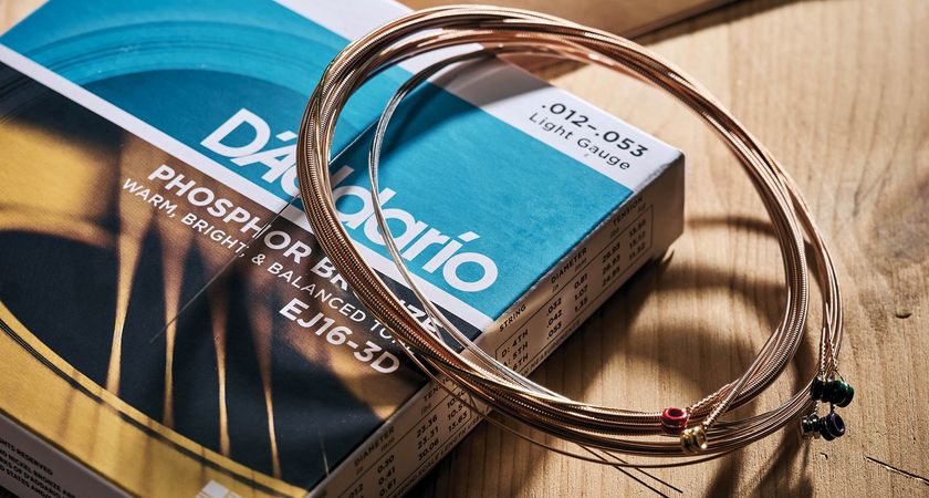 A set of D&#039;Addario guitar strings photographed against a light wood background.