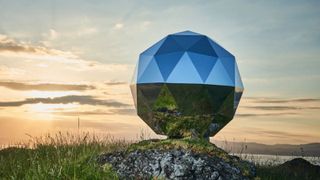 We see a huge "humanity star" that looks like a giant reflective ball in a field at sunrise.