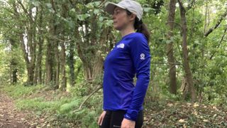 Trail runner in the woods wearing a blue top