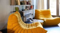 gray living room with open-shelf book shelf, two yellow togo armchairs, and french doors opening to garden
