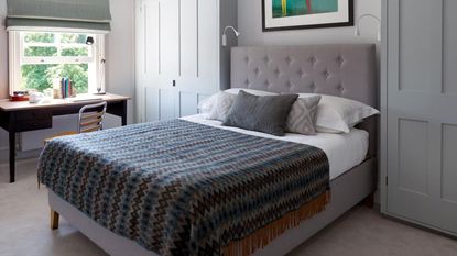 Bedroom with double bed with grey padded headboard, fitted wardrobes either side and a desk beside an open sash window. Christine and Tim Mason's renovated Victorian townhouse in Barnes, London.