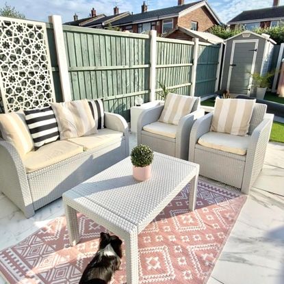 garden furniture with a sofa, two armchairs and coffee table on a pink outdoor geometric rug 