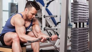 Young bodybuilder using a cable machine for forearm curls