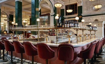 Central bar surrounded by red leather bar stools and pillars with green verdite