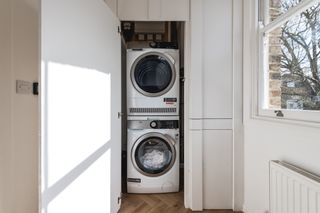 Small utility room ideas showing stacked washing appliances discretely concealed behind a cupboard door