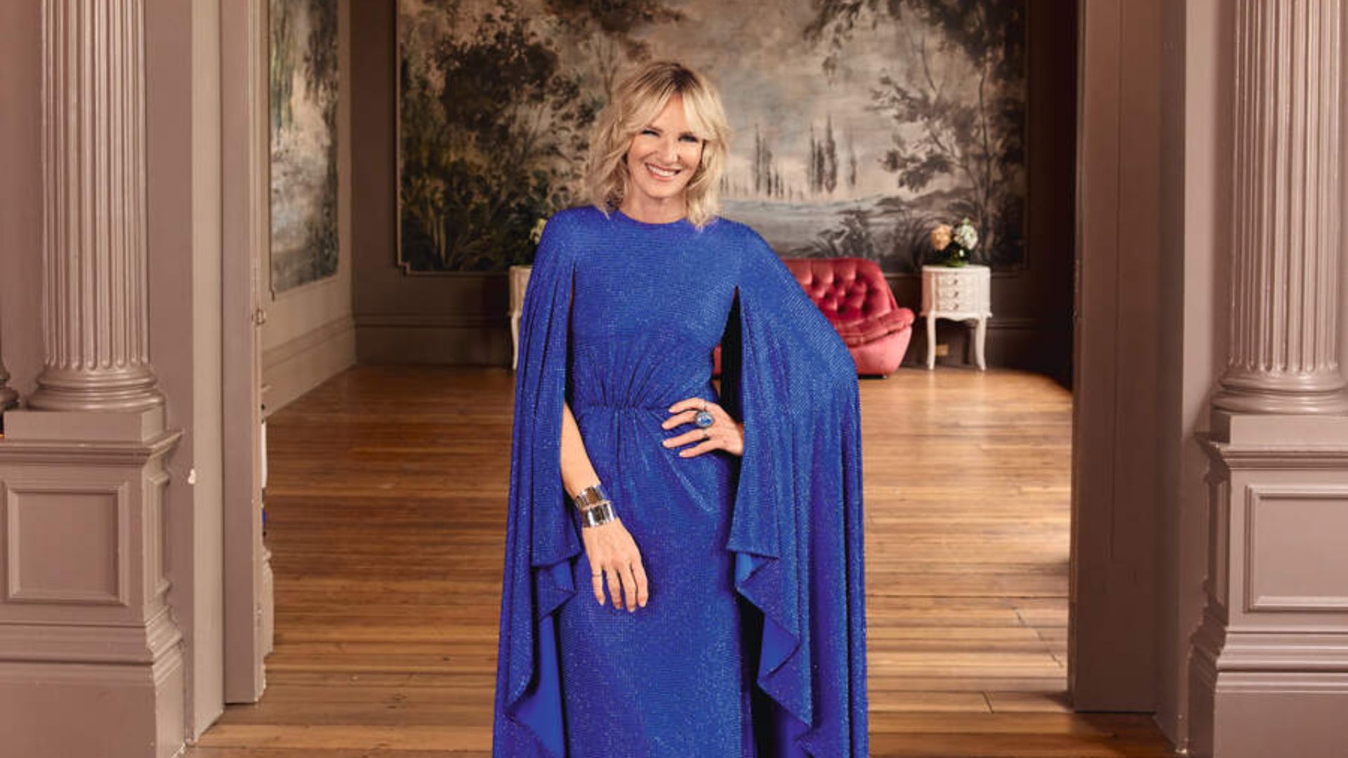 Jo Whiley poses in a blue cape sleeve dress 