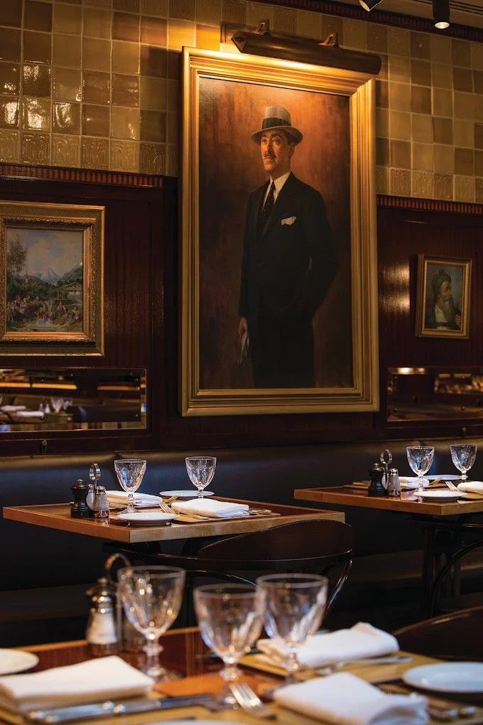 A Vienna-style, Art Deco cafe with gilded framed artworks, wooden furniture, and glassy details.