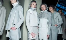 Models backstage wearing all white outfits, coat with sports jacket, matching skirt and jackets