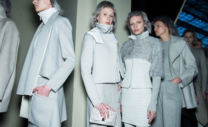 Models backstage wearing all white outfits, coat with sports jacket, matching skirt and jackets