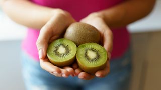 halved kiwi fruit in a woman's hand