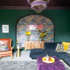 An emerald green-painted living room with a dark purple ceiling and a dark blue corner sofa