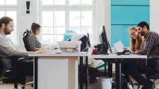 Image of office space with colleagues working at workstations opposite each other