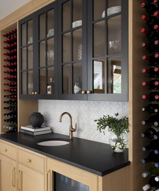home bar with dark worktops and shelves and pale wood cabinetw