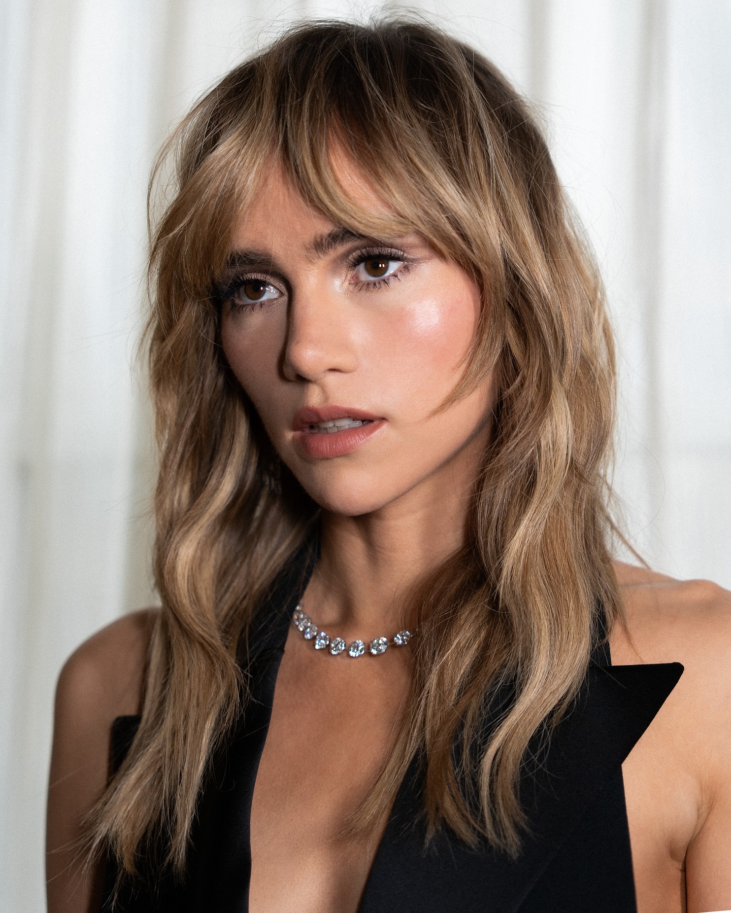 Suki Waterhouse with Birkin bangs, wearing a black halterneck top