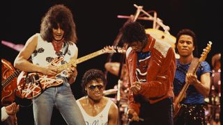 Eddie Van Halen plays guitar on stage with Randy Jackson, Michael Jackson and Jermaine Jackson during the Victory Tour