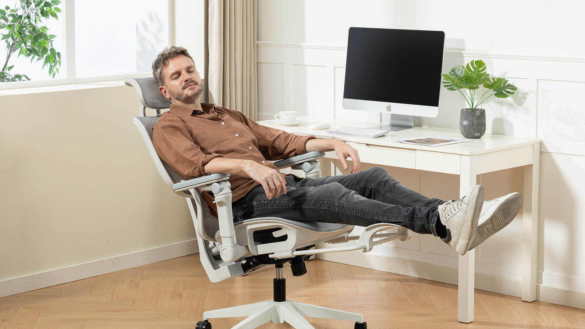 A man reclining on the Boulies EP600 chair in his home office