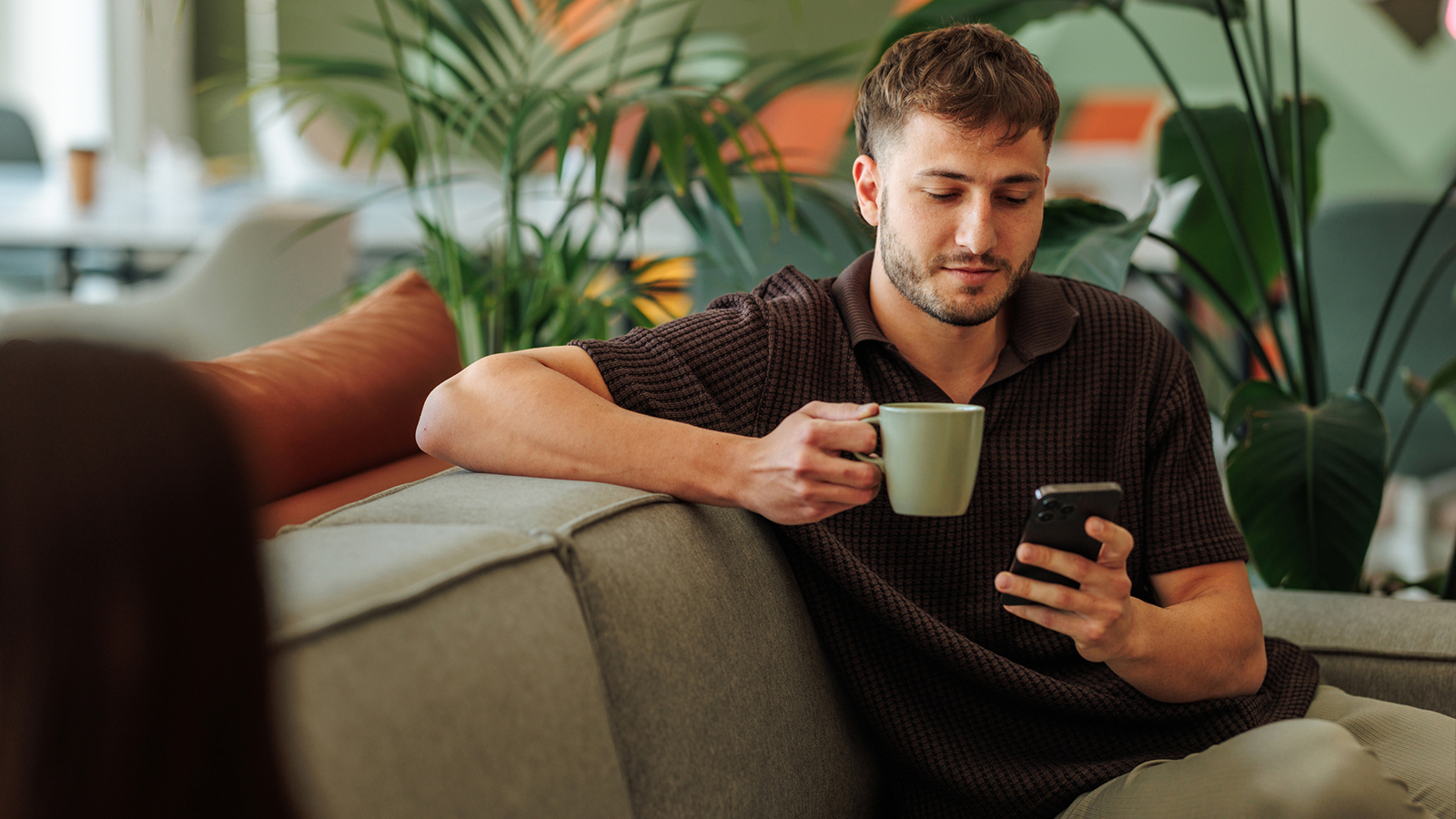 man looking at smartphone on sofa