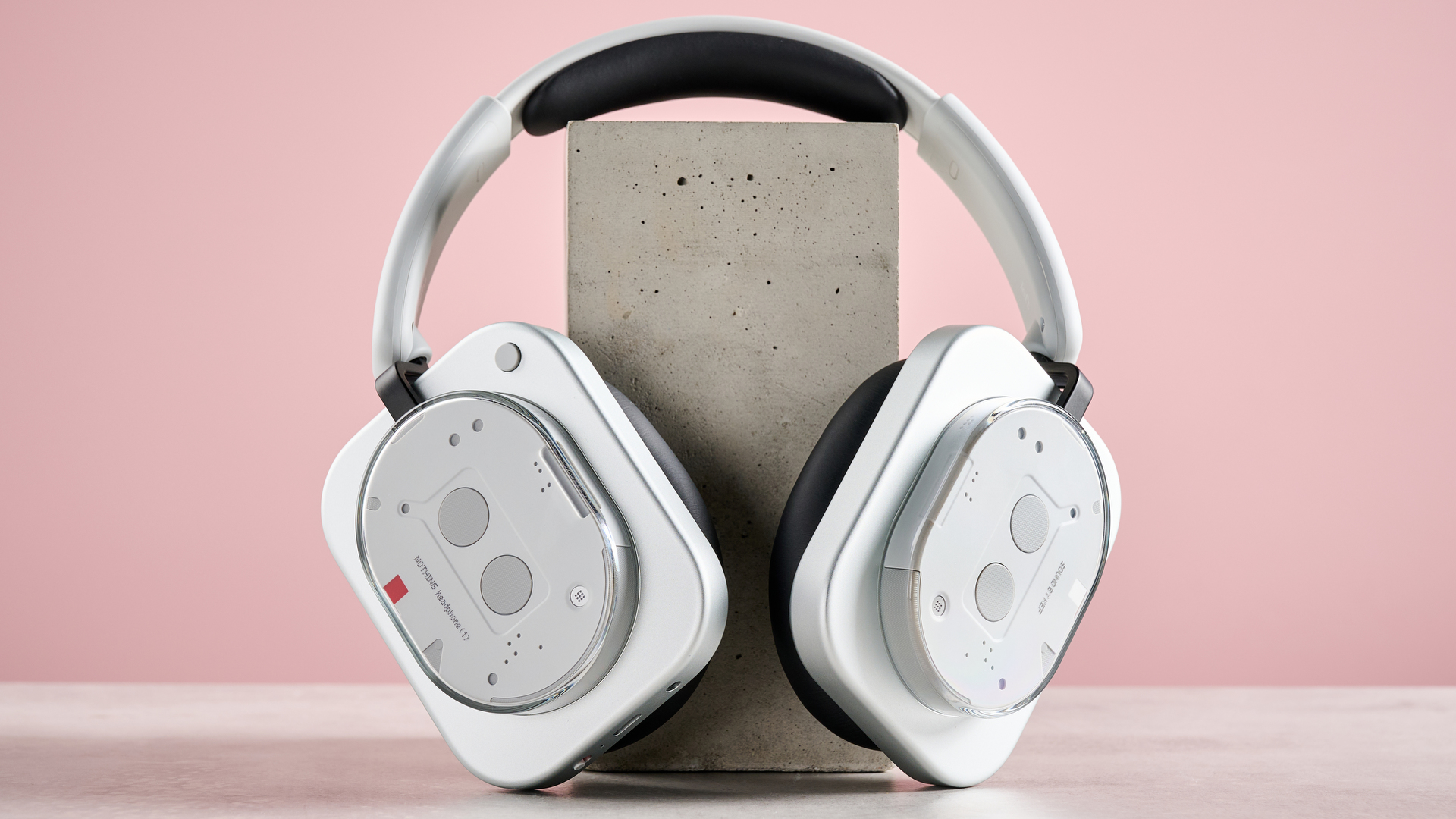 The Nothing Headphone (1) leaning against a pink wall