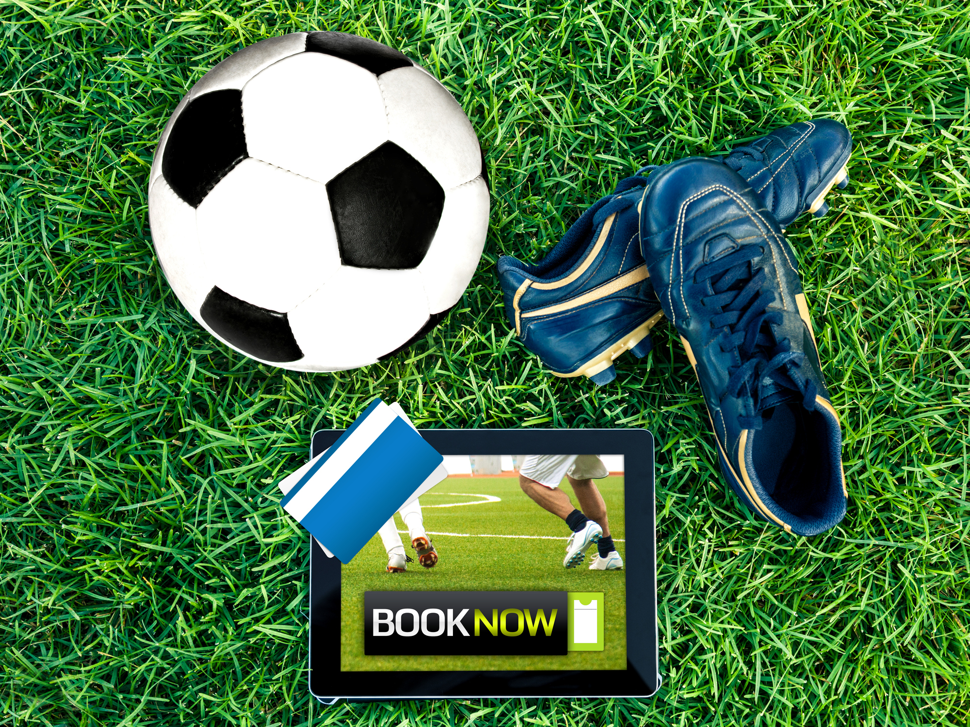 a picture of a soccer ball, cleats, a credit card and a tablet showing someone purchasing soccer tickets