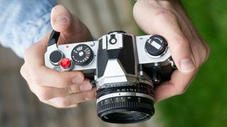 Man holding Nikon FM, winding film on