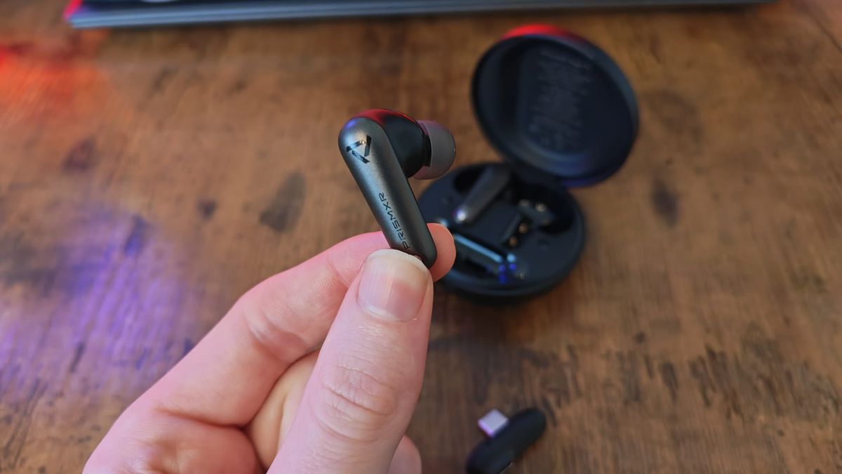 A reviewer holding the left PrismXR Vega T1 earbud
