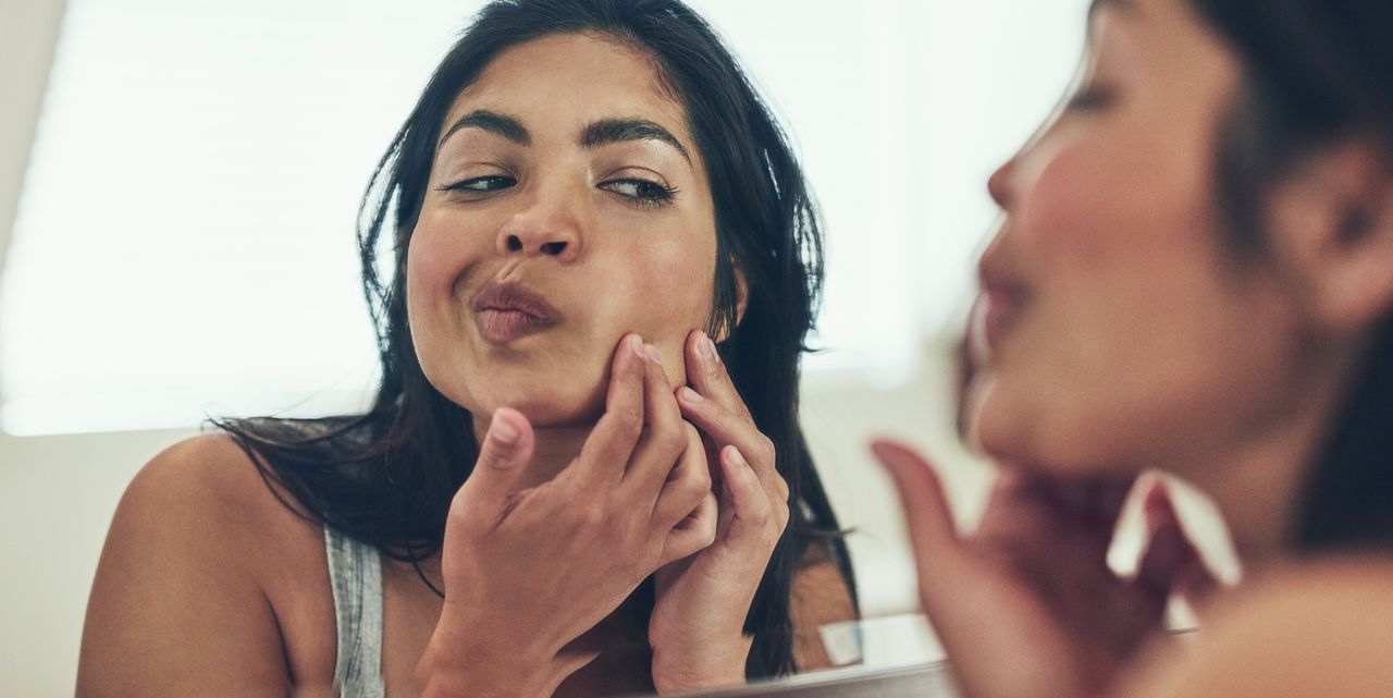 Woman looking at her skin in the mirror