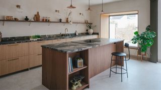 Warm wood cabinetry and a stone-topped island give this kitchen a natural, contemporary feel. Open shelving and soft lighting keep the space airy while adding practical storage.