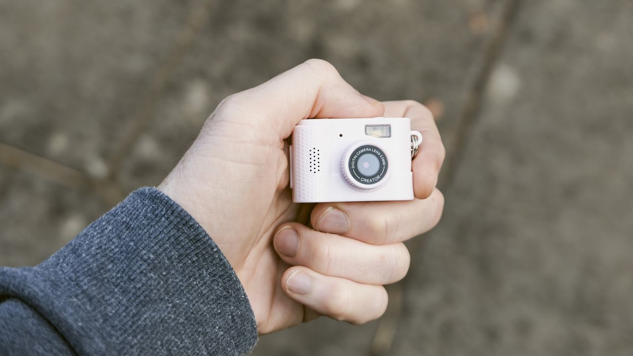 Miniature pink keychain camera, the 'Photo Creator Mini Digital Camera series 3', in user's hand