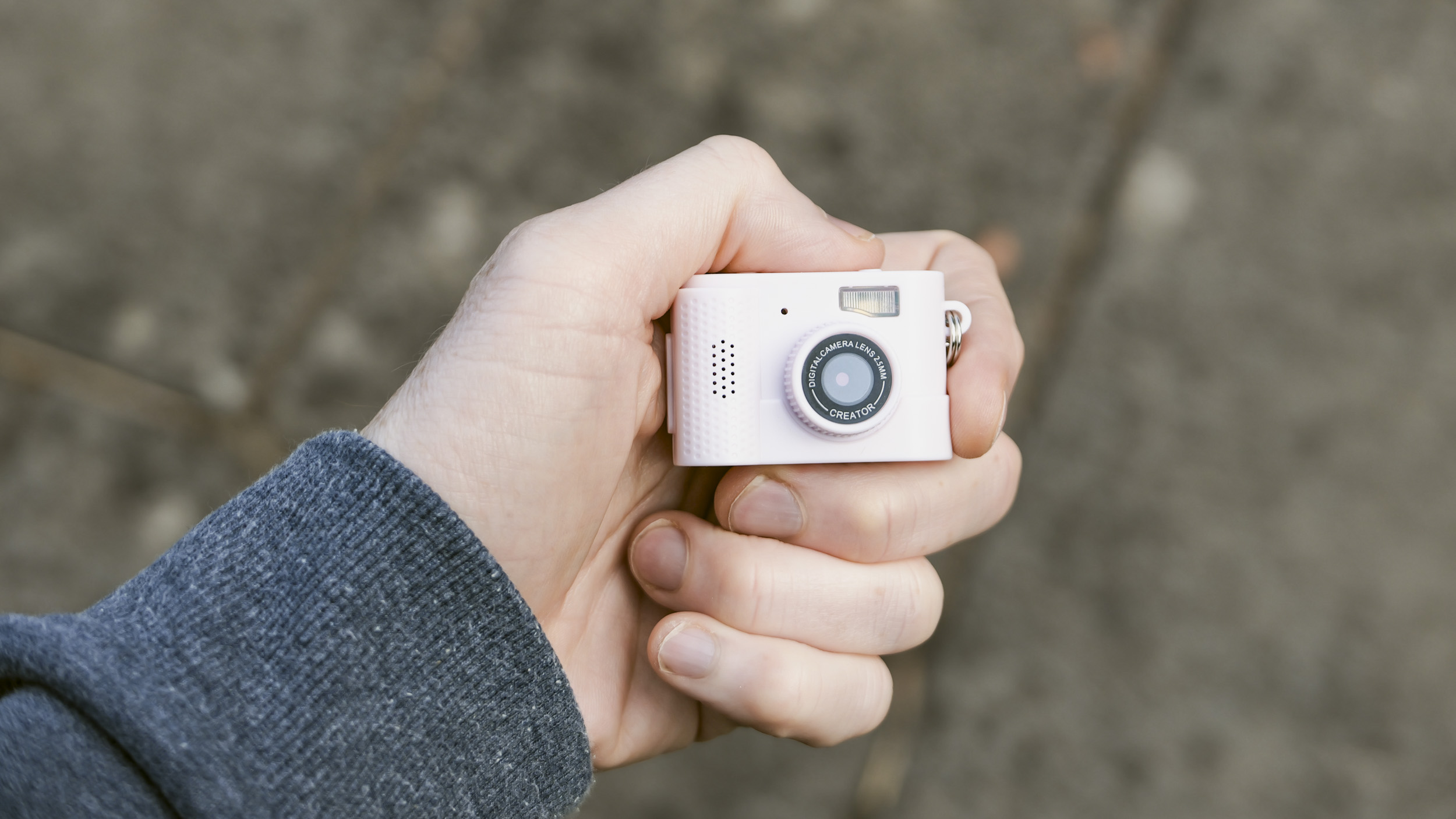 Miniature pink keychain camera, the 'Photo Creator Mini Digital Camera series 3', in user's hand