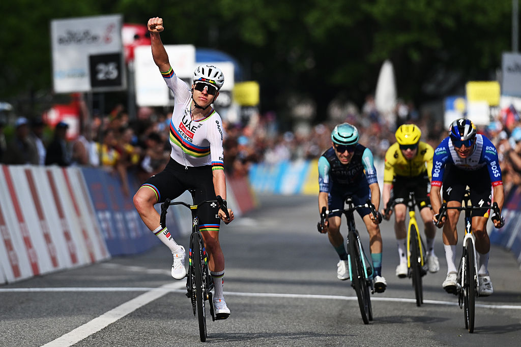 Tadej Pogacar raises his arm in celebration as three breakaway riders finish behind