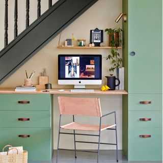under stair study area with small desk and green cabinets