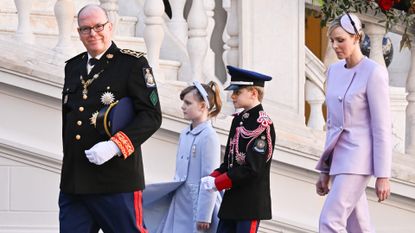 Prince Albert, Princess Gabriella, Prince Jacques and Princess Charlene wearing dress coats and military uniforms outside the palace in Monaco