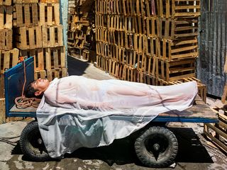 Man lying under wet sheet on a cart