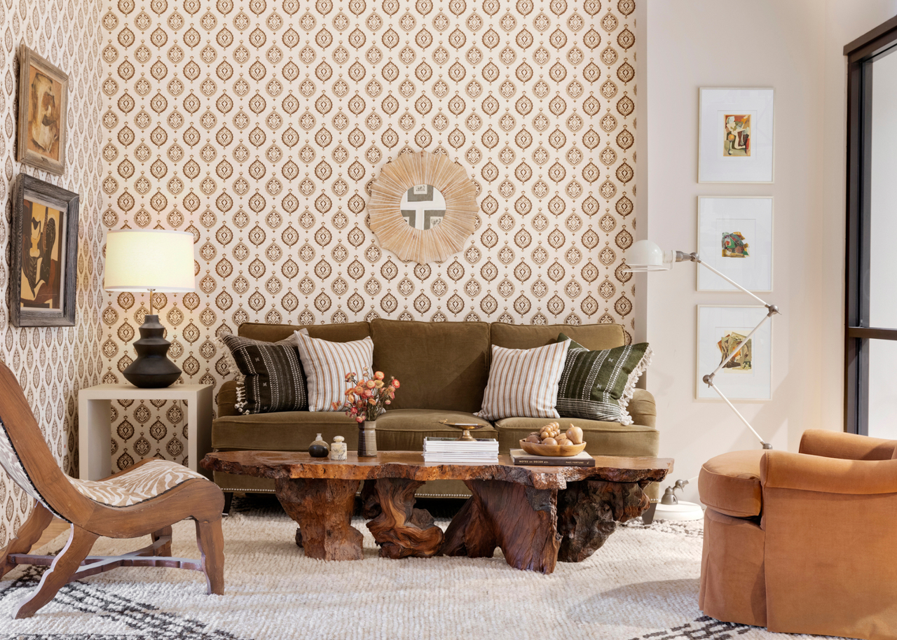 Heather Peterson's living room with burl wood coffee table, a green sofa and two chairs with two walls plastered in wallpaper