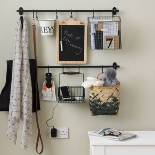 hallway storage hooks in black against a cream wall with white table