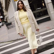 ana wears pale yellow sweater and skirt with beige blazer and white mesh flats