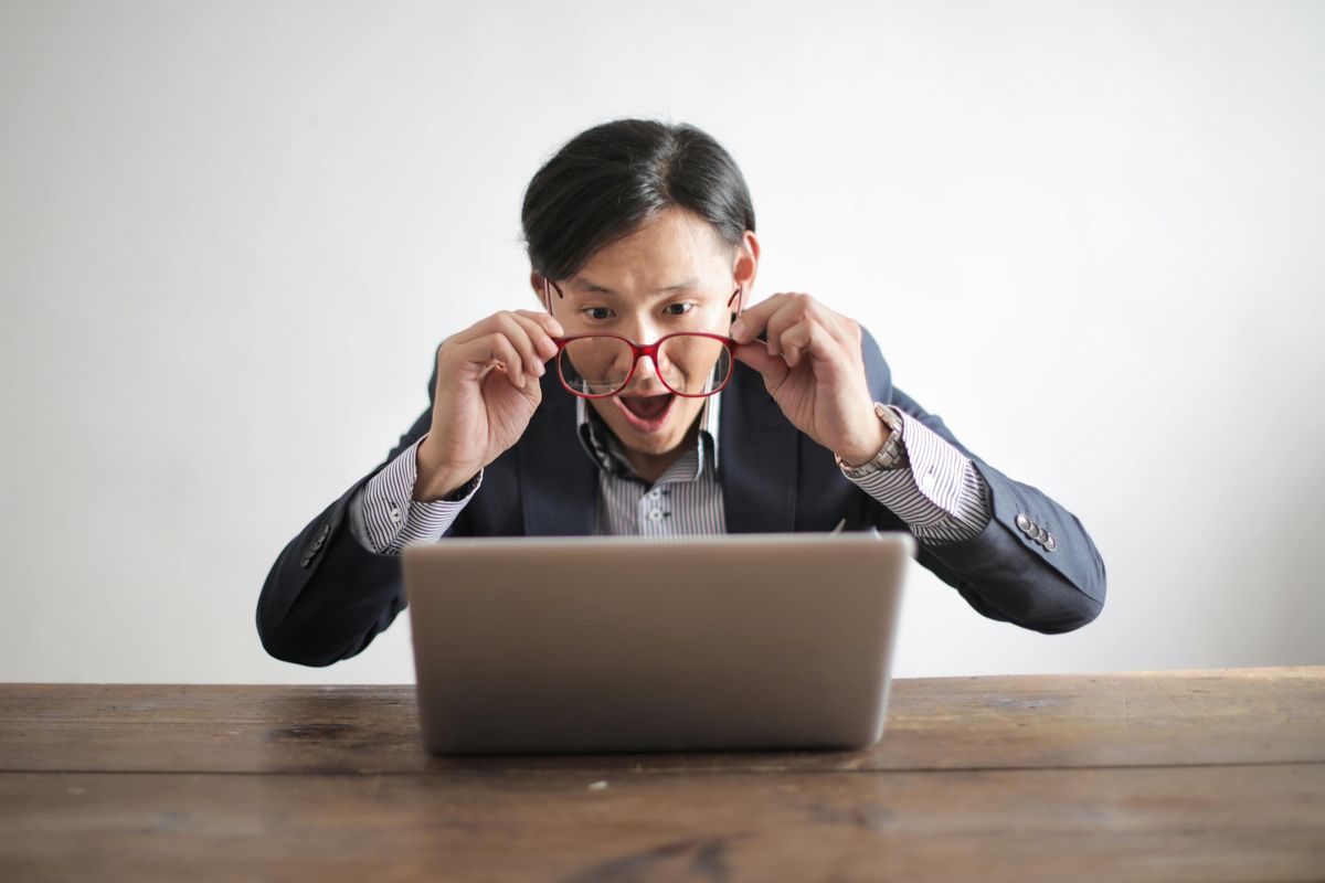 Man looking at laptop with shocked expression on face