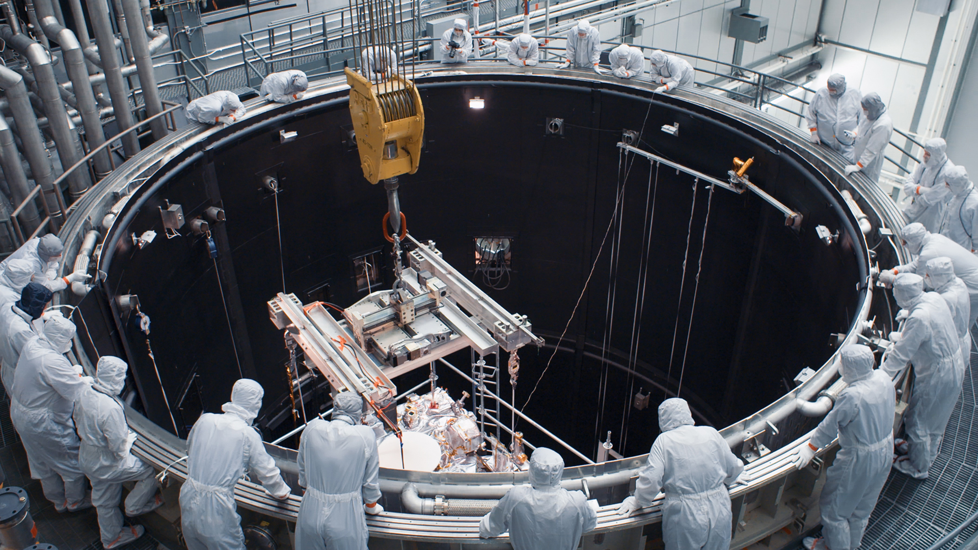 Technicians gather around Lockheed Martin’s thermal vacuum chamber to watch the OSIRIS-REx spacecraft enter one of its last phases of testing.