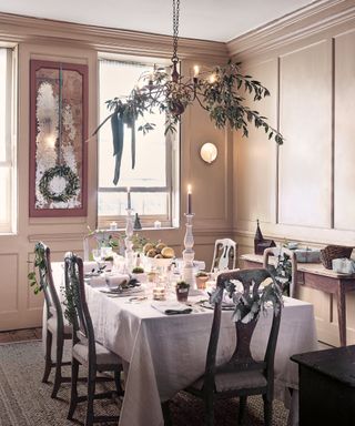 Dining room decorated with christmas decorations, garland suspended over dining table