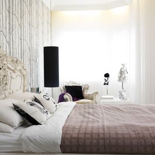 bedroom with white wall and curtains and bedding with cushions and throw