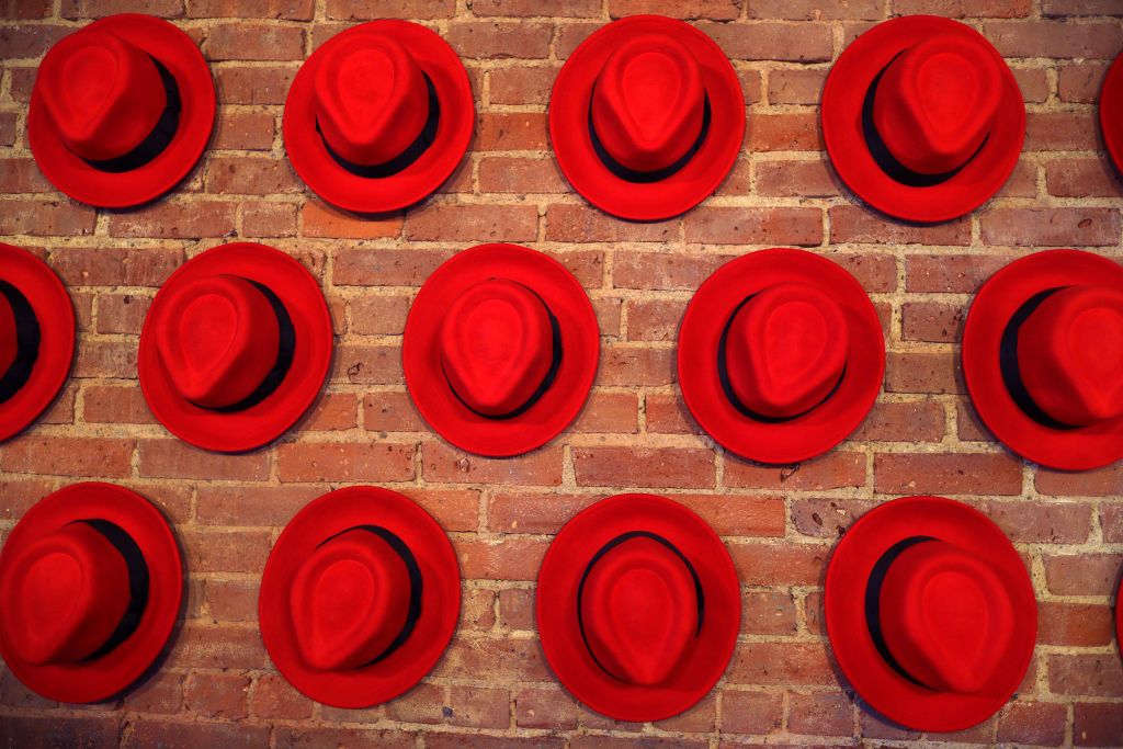 Red Hat Enterprise Linux (RHEL): Three rows of red hats hanging on a bare brick wall