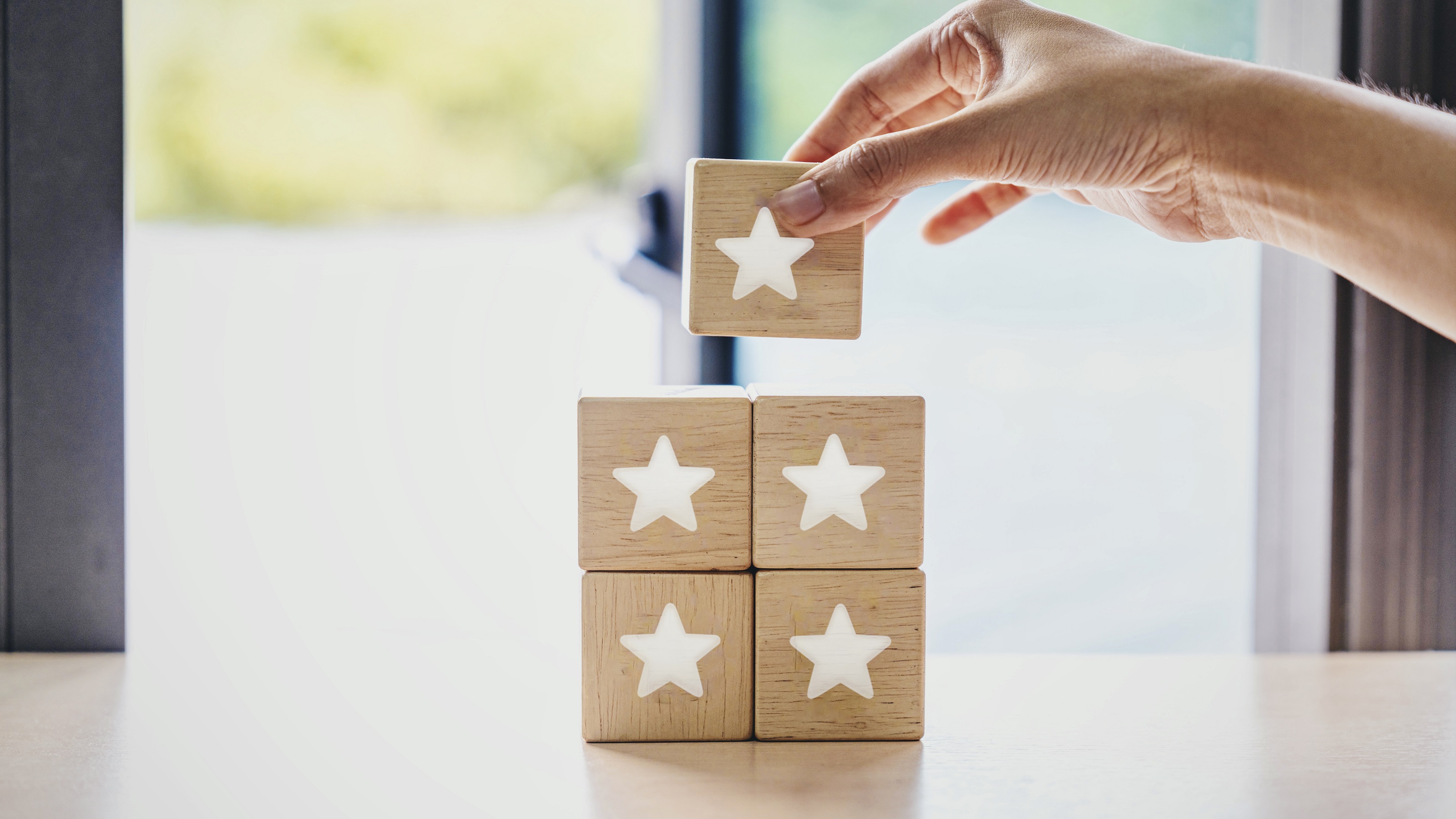 Five wooden blocks with white stars being stacked by a woman. 