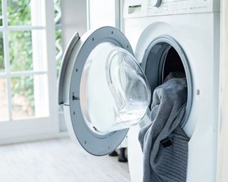 Washing machine with its door open and laundry spilling out