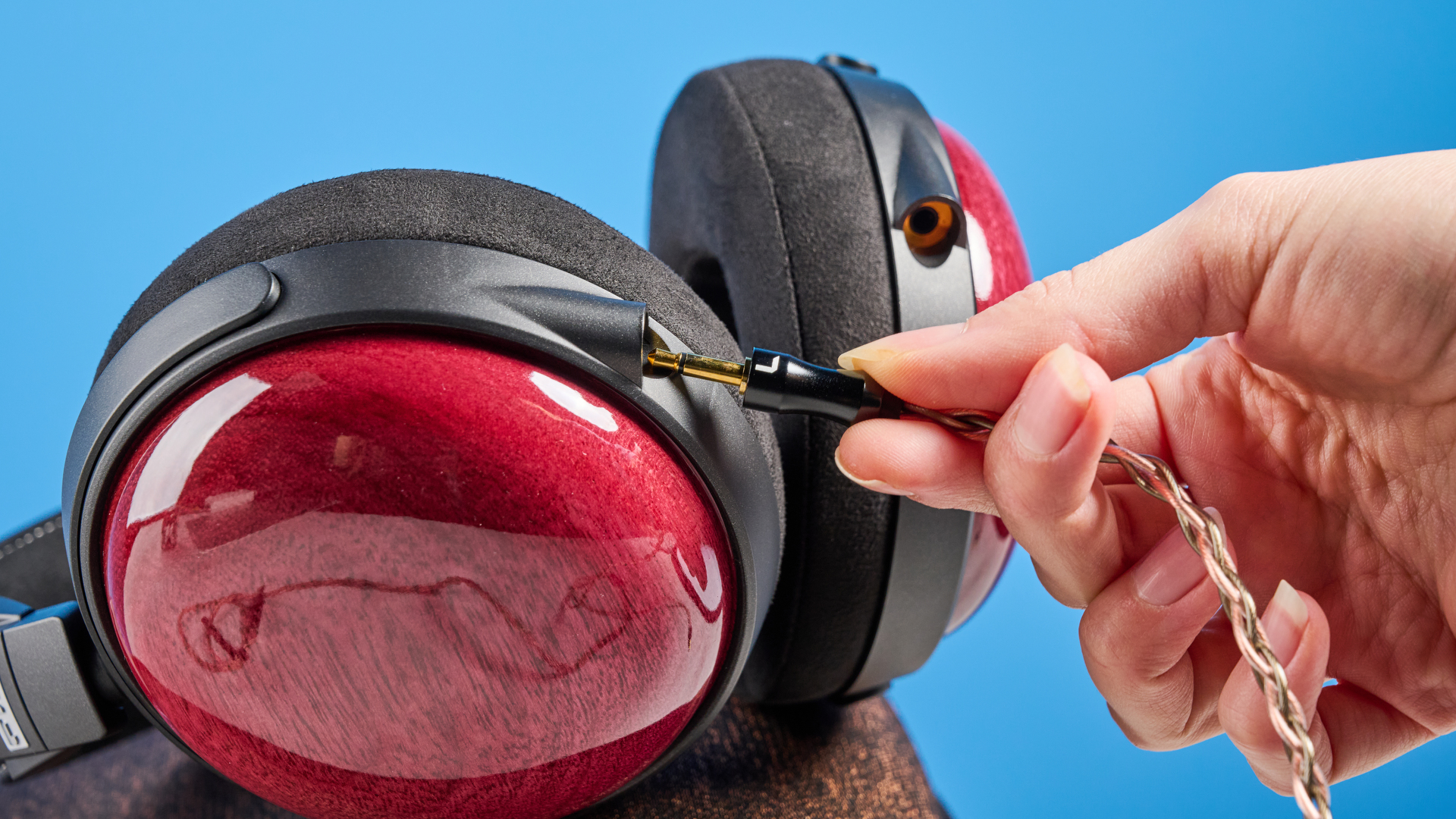 the fiio ft13 wired headphones with wood cups and copper cable photographed against a blue background