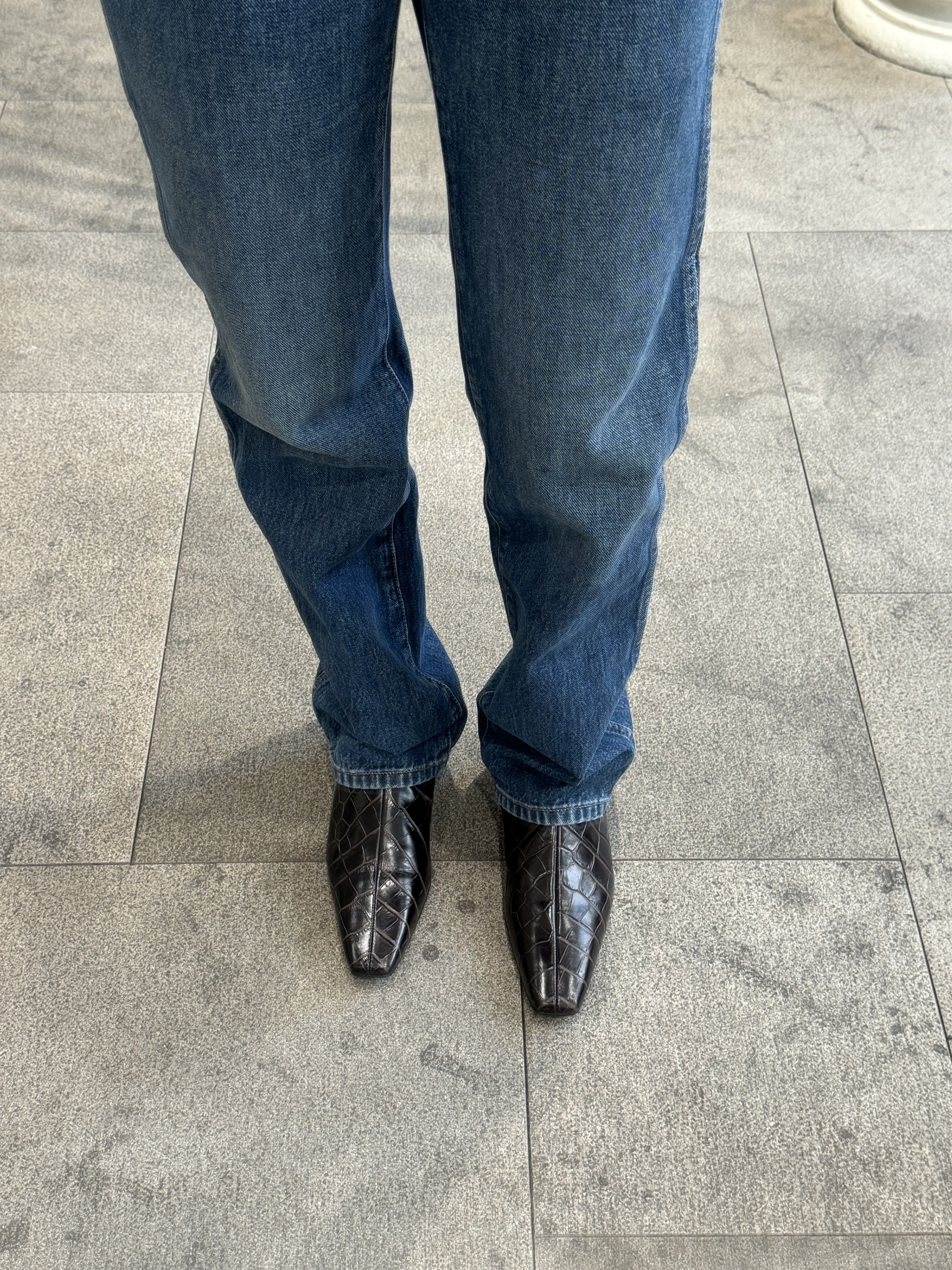 Nikki wears blue jeans and toteme croc-embossed boots.