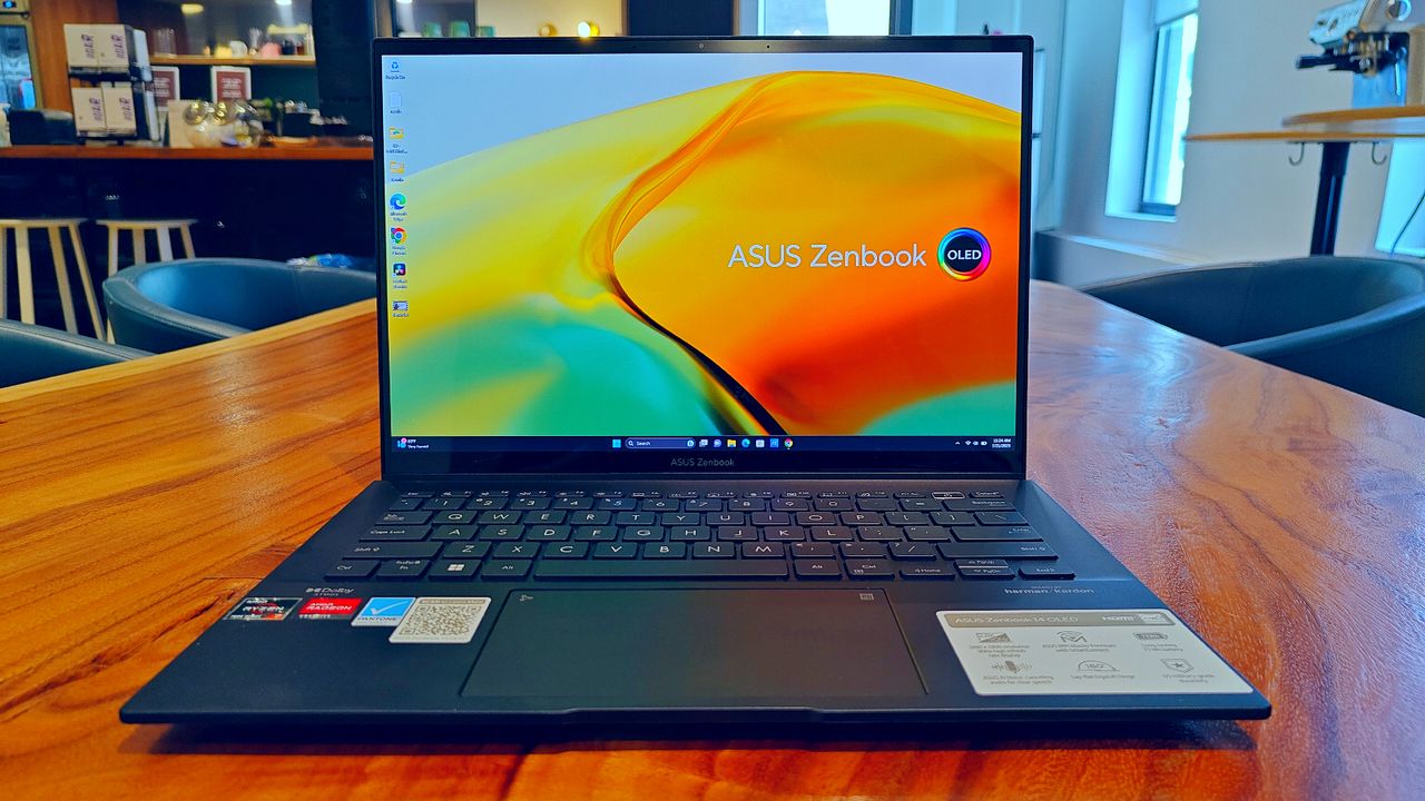 Asus Zenbook 14 OLED UM3402Y open on a wooden desk with the desktop on the display.
