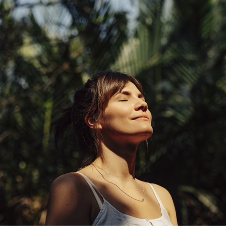 Woman with face in the sunshine surrounded by tropical banana leaves