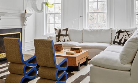 White living room with corner sofa, abstract graphic black and white cushions, wood coffee table and cobalt blue Wiggle side chairs